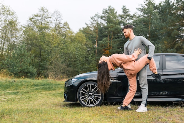 Couple dancing in nature near their car.