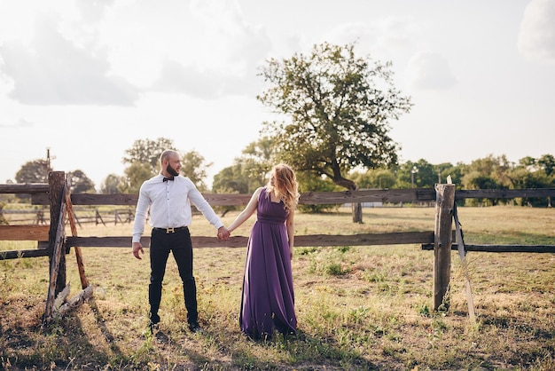 Foto coppia ad un appuntamento. vestito viola. sposa e sposo. cammina nel campo. storia d'amore.