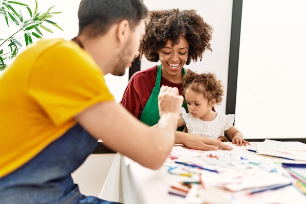 Couple and daughter smiling confident drawing at art studio