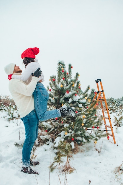 Couple decorating christmas tree outdoors snowed winter outdoors