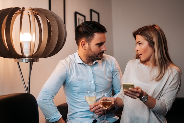 Couple discussing something at home. Drinking white wine.