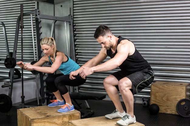 Couple doing box jumps in gym at gym