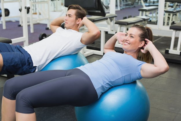 Couple doing sit ups on exercise balls