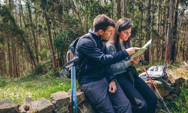 Couple doing trekking sitting looking at a map