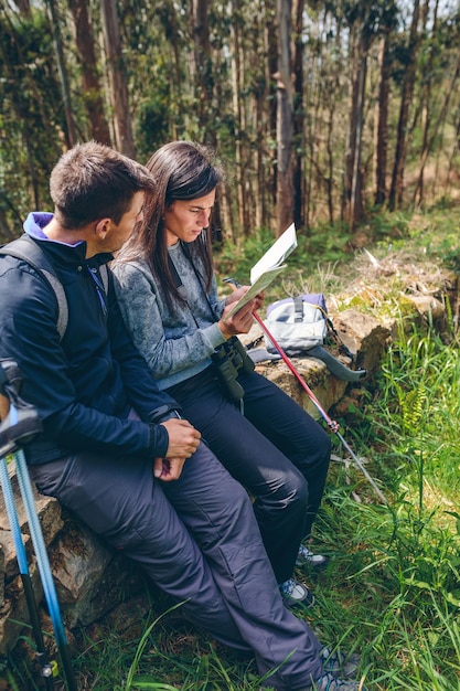 Couple doing trekking sitting looking at a map