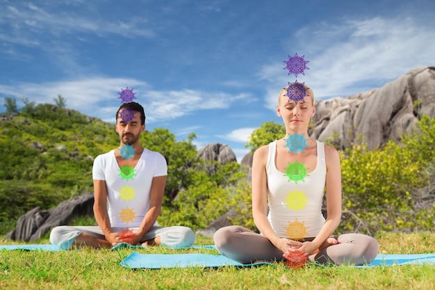 couple doing yoga in lotus pose with seven chakras