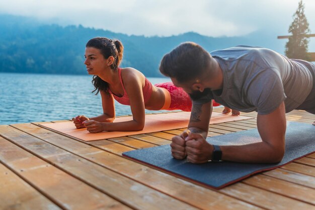 Couple doing a yoga near lake early in the morning