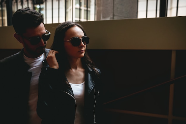 A couple dressed in black and white with sunglasses on their eyes in city. Street love story