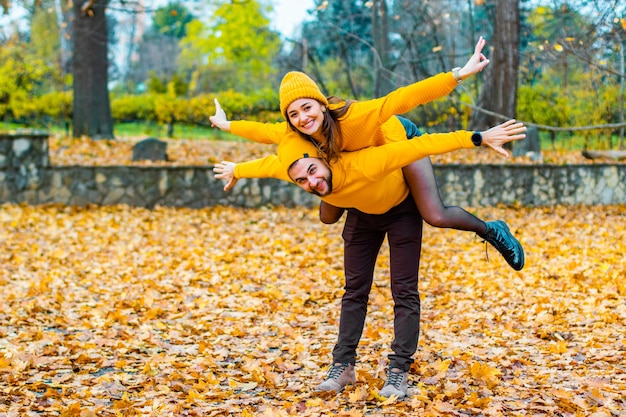Couple dressed in yellow turtlenecks and yellow hats in the park in autumn