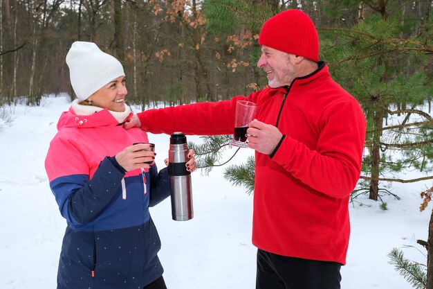Пара пьет теплые напитки в зимнем парке