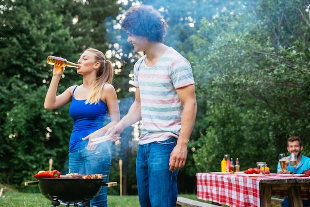 Couple drinking beer and making barbecue together