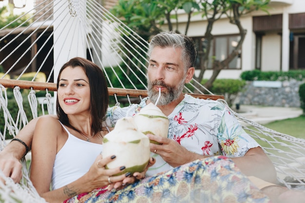 Couple drinking coconut juice in a hammock