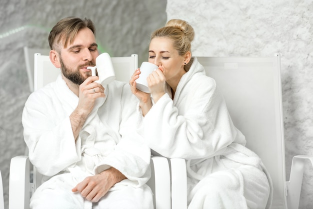 Couple drinking mineral water sitting in the salt room. Applying salt therapy in the Spa