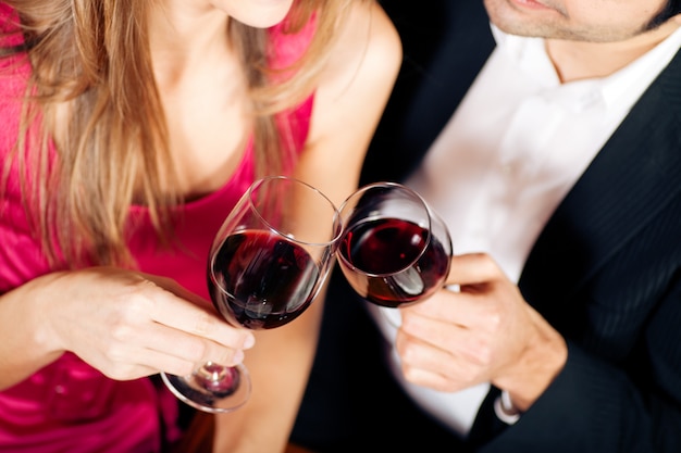 Couple drinking red wine clinking glasses