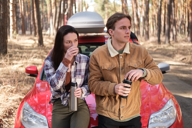 Couple drinking tea near the car