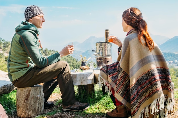 Couple drinking turkish tea from glasses and samovar outdoors, mountain view on Lycian way in Turkey. Man and woman on romantic vacation