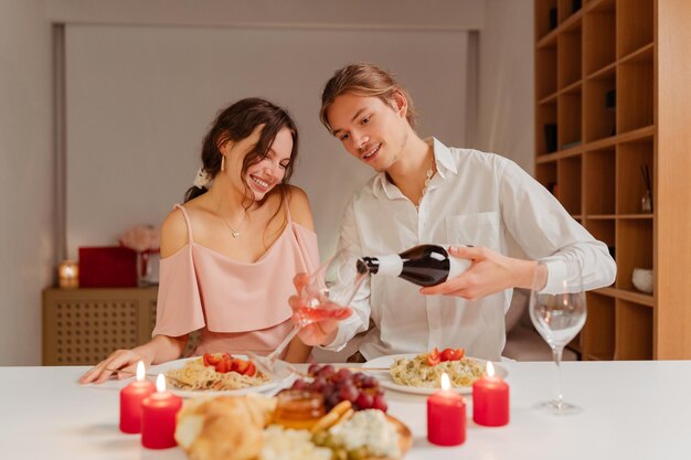 Foto coppia che beve vino, mangia cibo, celebra san valentino a casa, si incontri, ama, cena romantica.