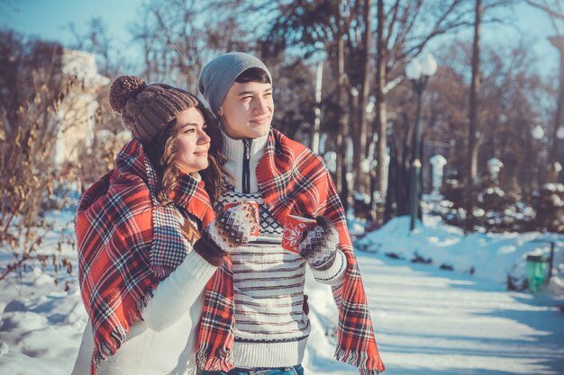 Couple drinks hot tea in winter park