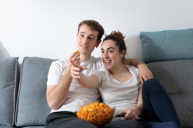 Couple eating candy on couch Bad eating habits concept