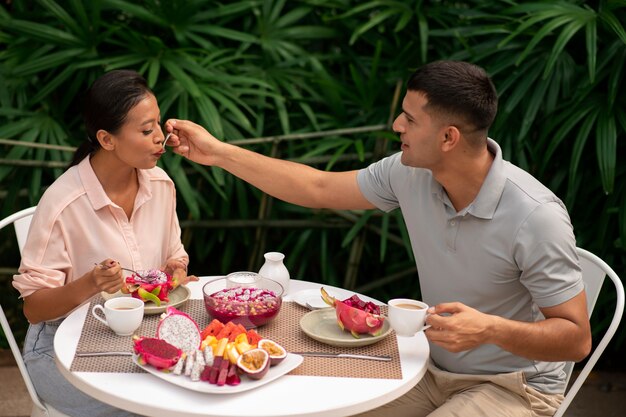 Photo couple eating dragon fruit outdoors together