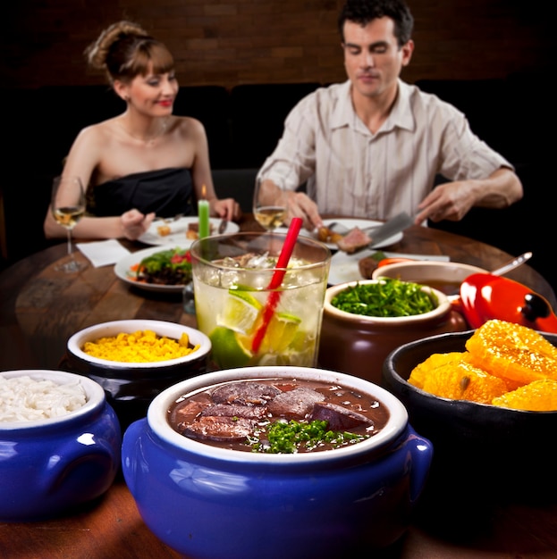 Couple eating feijoada at the restaurant.
 Traditional Brazilian feijoada with cabbage and rice