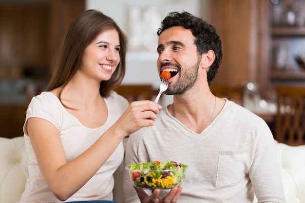 Couple eating a salad in the living room. 