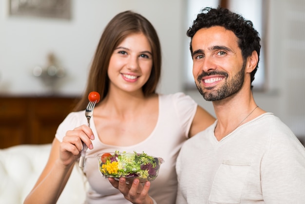 Couple eating a salad in the living room