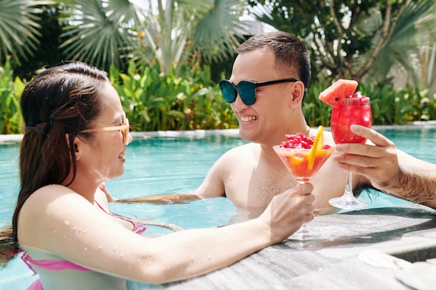 Couple eating smoothie in swimming pool