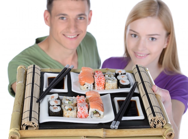 Couple eating sushi while sitting close to each other.