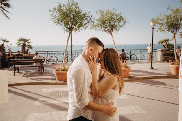 A couple embraces in front of a beach