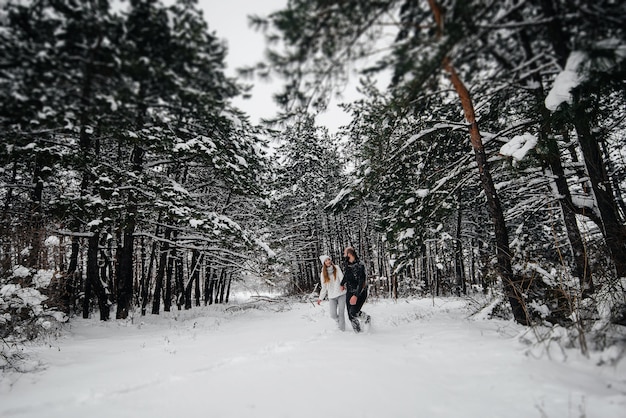 木を背景に雪に覆われた森の中で抱き合うカップル