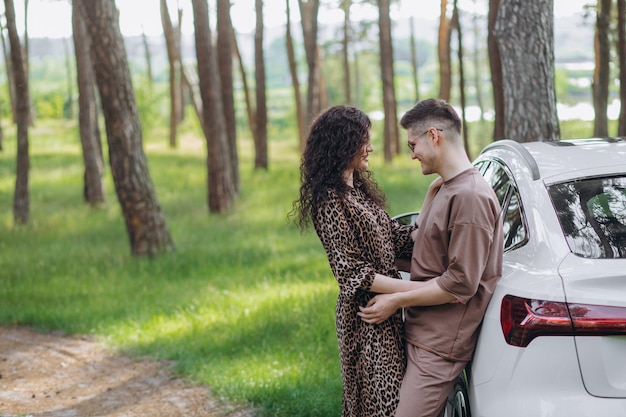 Couple embracing each other in the forest near modern car