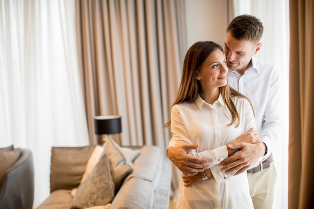 Couple embracing standing in living room of a contemporary apartment