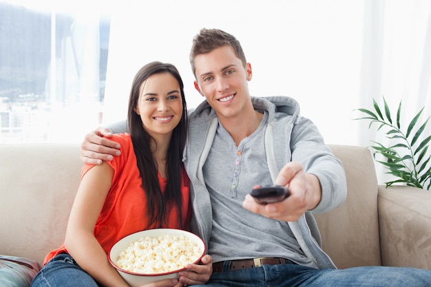 A couple embracing while on the couch changing the channel 