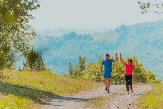 Couple enjoying in a healthy lifestyle while jogging on a country road through the beautiful sunny forest, exercise and fitness concept