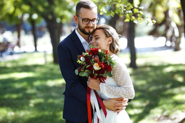 Couple enjoying romantic moments in park Elegant bride in beautiful white dress groom in a suit