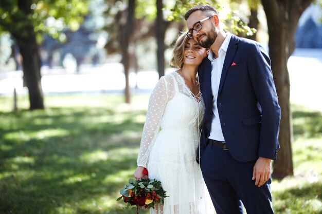 Couple enjoying romantic moments in park Elegant bride in beautiful white dress groom in a suit