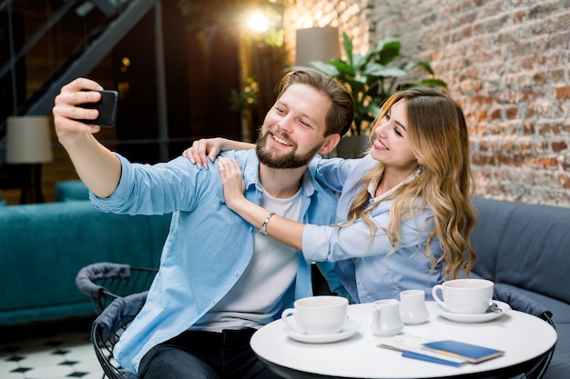 カップルが一緒に時間を楽しんで、selfieを作り、カフェのテーブルに座って、コーヒーを飲みます。