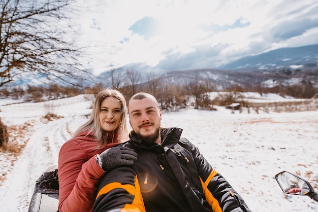 Couple enjoying while driving quad bike on top of mountain at winter time