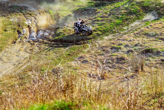 Couple enjoys riding an ATV on forest hills