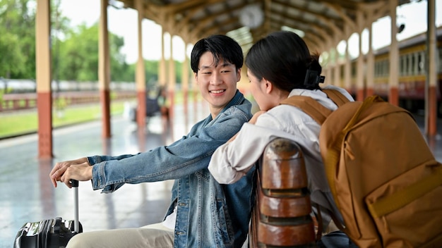 Пара наслаждается разговором на скамейке на платформе перед совместной посадкой в поезд