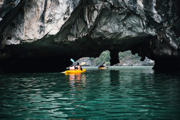 카약을 타고 동굴을 탐험하고 보트 하롱베이 베트남 깟바 섬에서 사진을 찍는 커플