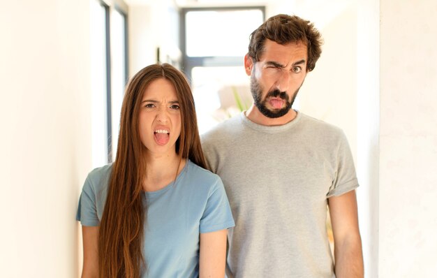 Photo couple  feeling disgusted and irritated, sticking tongue out, disliking something nasty and yucky