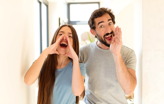 Photo couple  feeling happy, excited and positive, giving a big shout out with hands next to mouth, calling out