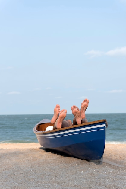 Piedi di coppia sulla barca sulla spiaggia