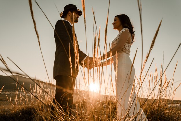 Couple in a field at sunset among dry plants