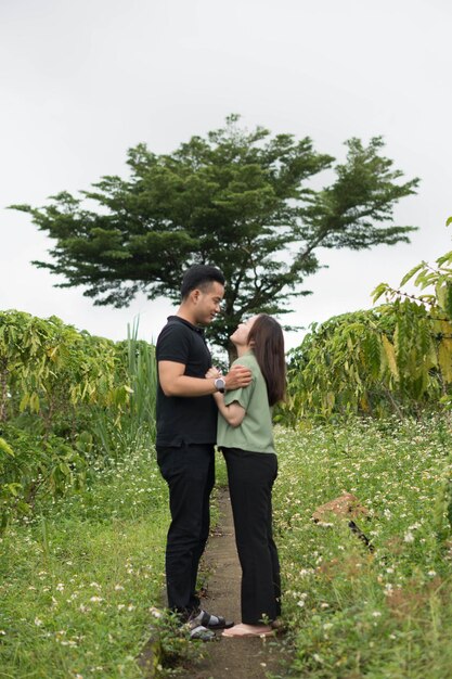 A couple in a field with trees in the background