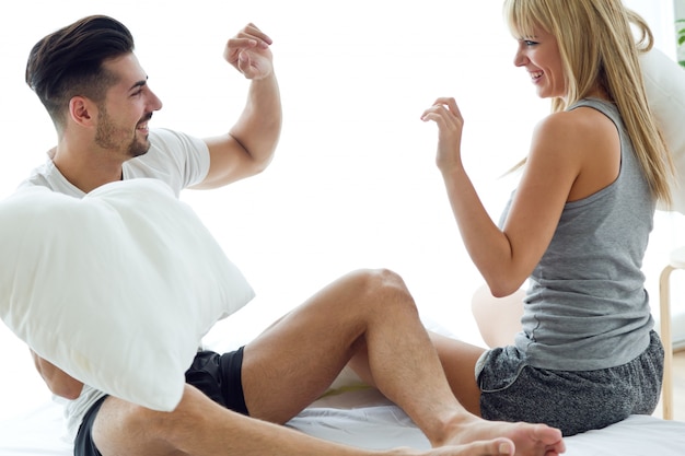 Couple fighting with pillows on bed