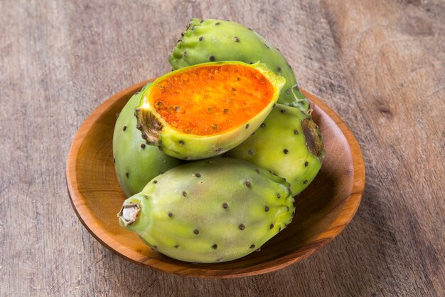 couple of Figs of India in a wooden pot over a wooden surface. Fresh fruit.