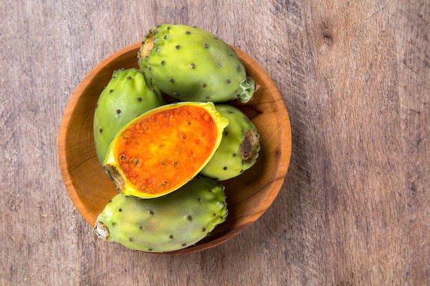 couple of Figs of India in a wooden pot over a wooden surface. Fresh fruit.